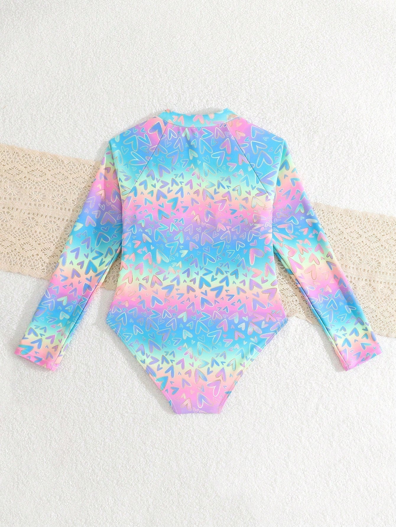 Tween girls one-piece rash guard swimsuit with long sleeves, high neck, front zipper, and ocean shell graphic print in a fitted style for beach, swimming, and vacation wear.