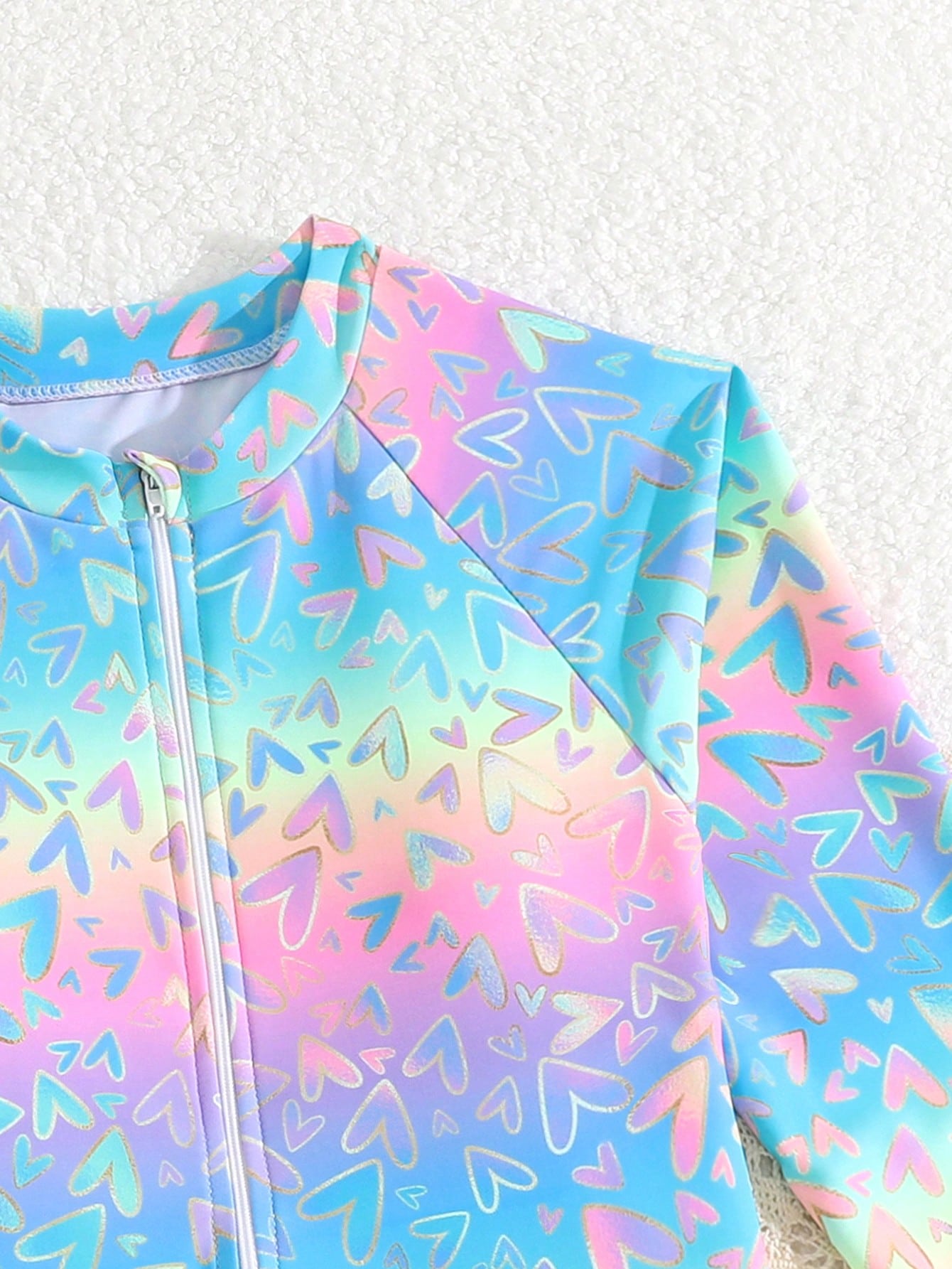 Tween girls one-piece rash guard swimsuit with long sleeves, high neck, front zipper, and ocean shell graphic print in a fitted style for beach, swimming, and vacation wear.