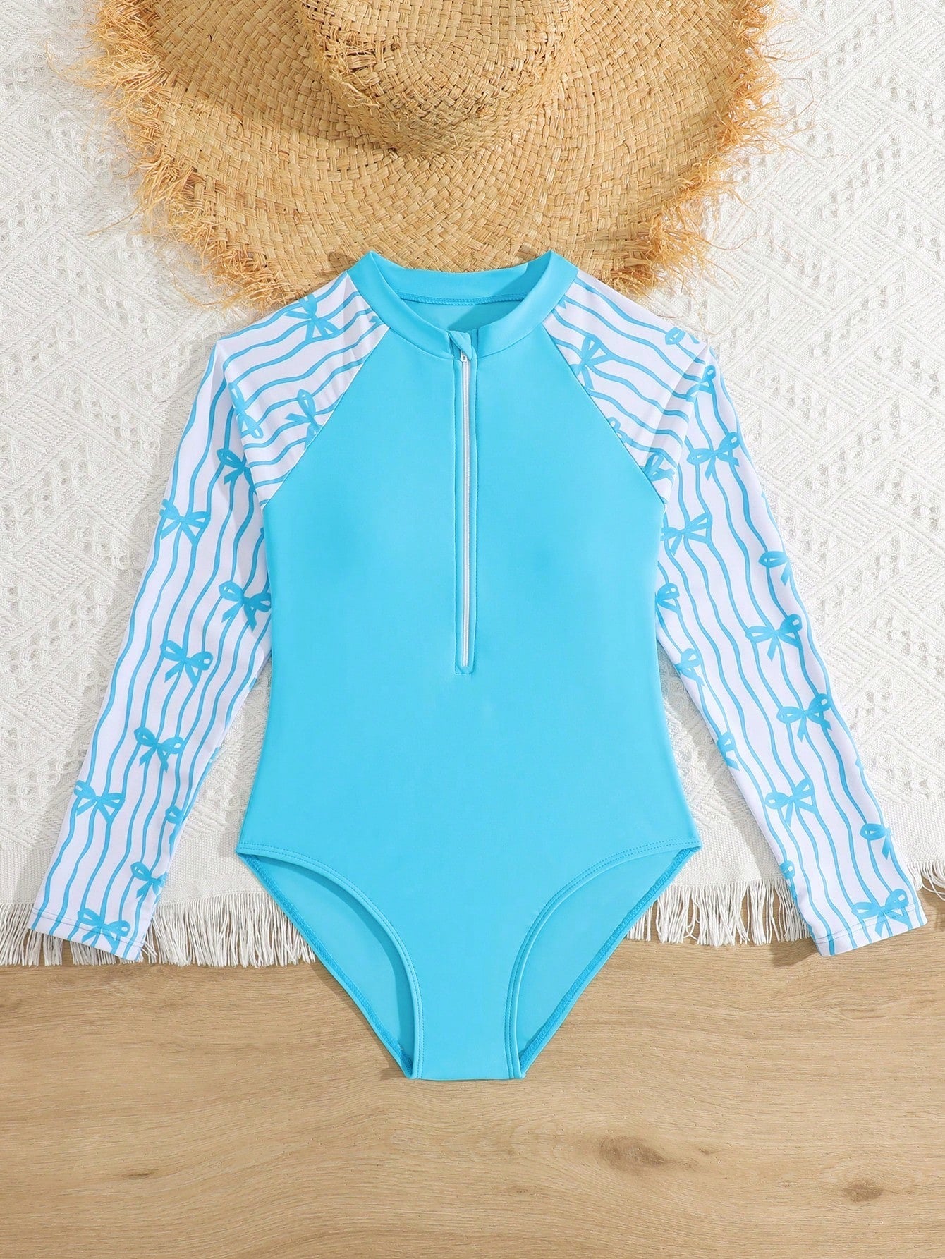 Tween girls one-piece rash guard swimsuit with long sleeves, high neck, front zipper, and ocean shell graphic print in a fitted style for beach, swimming, and vacation wear.