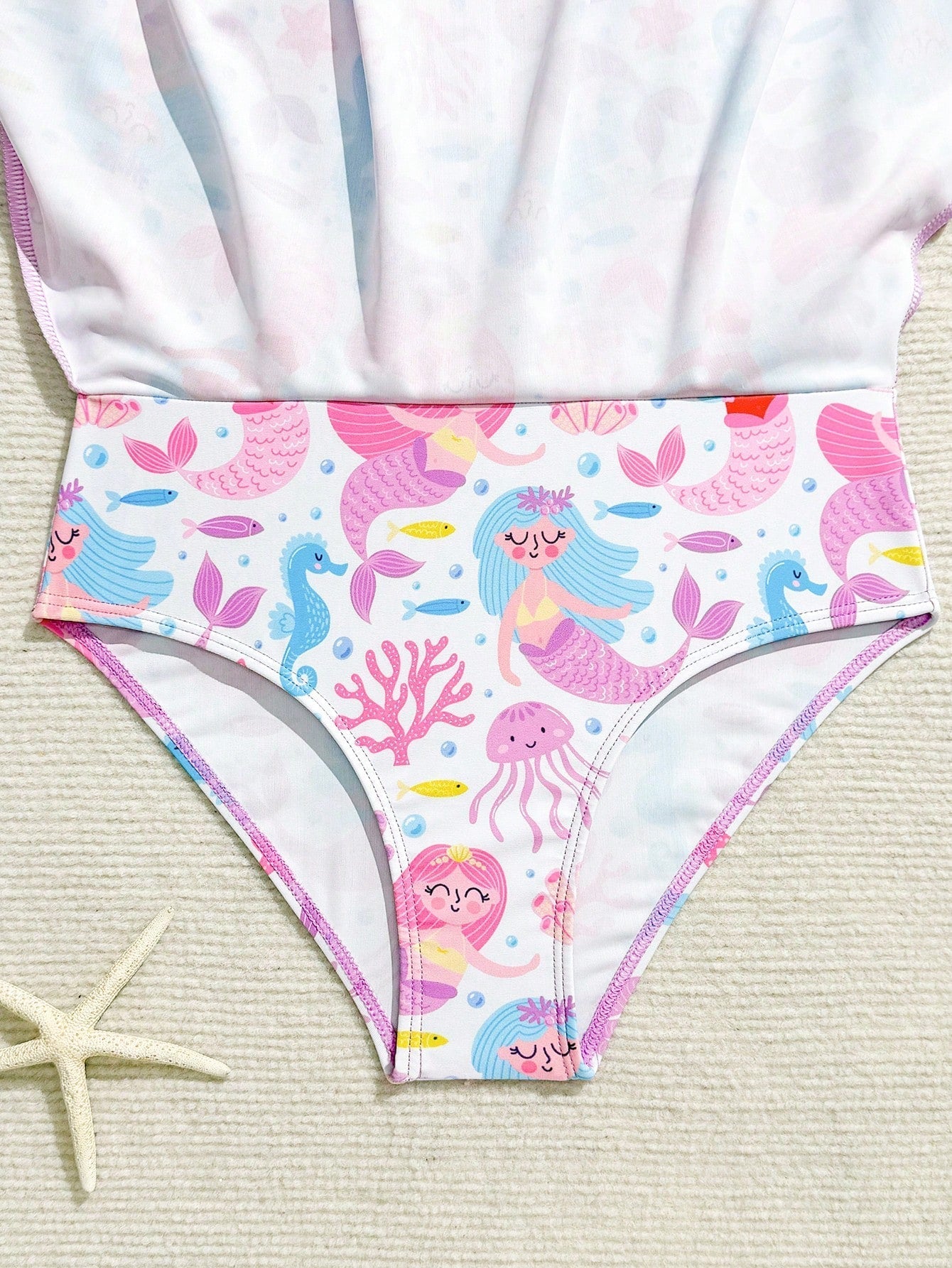 Tween girls one-piece rash guard swimsuit with long sleeves, high neck, front zipper, and ocean shell graphic print in a fitted style for beach, swimming, and vacation wear.