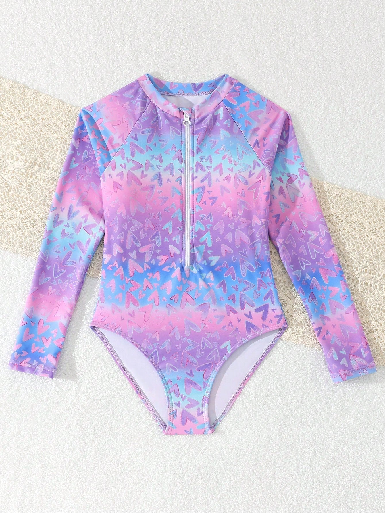 Tween girls one-piece rash guard swimsuit with long sleeves, high neck, front zipper, and ocean shell graphic print in a fitted style for beach, swimming, and vacation wear.