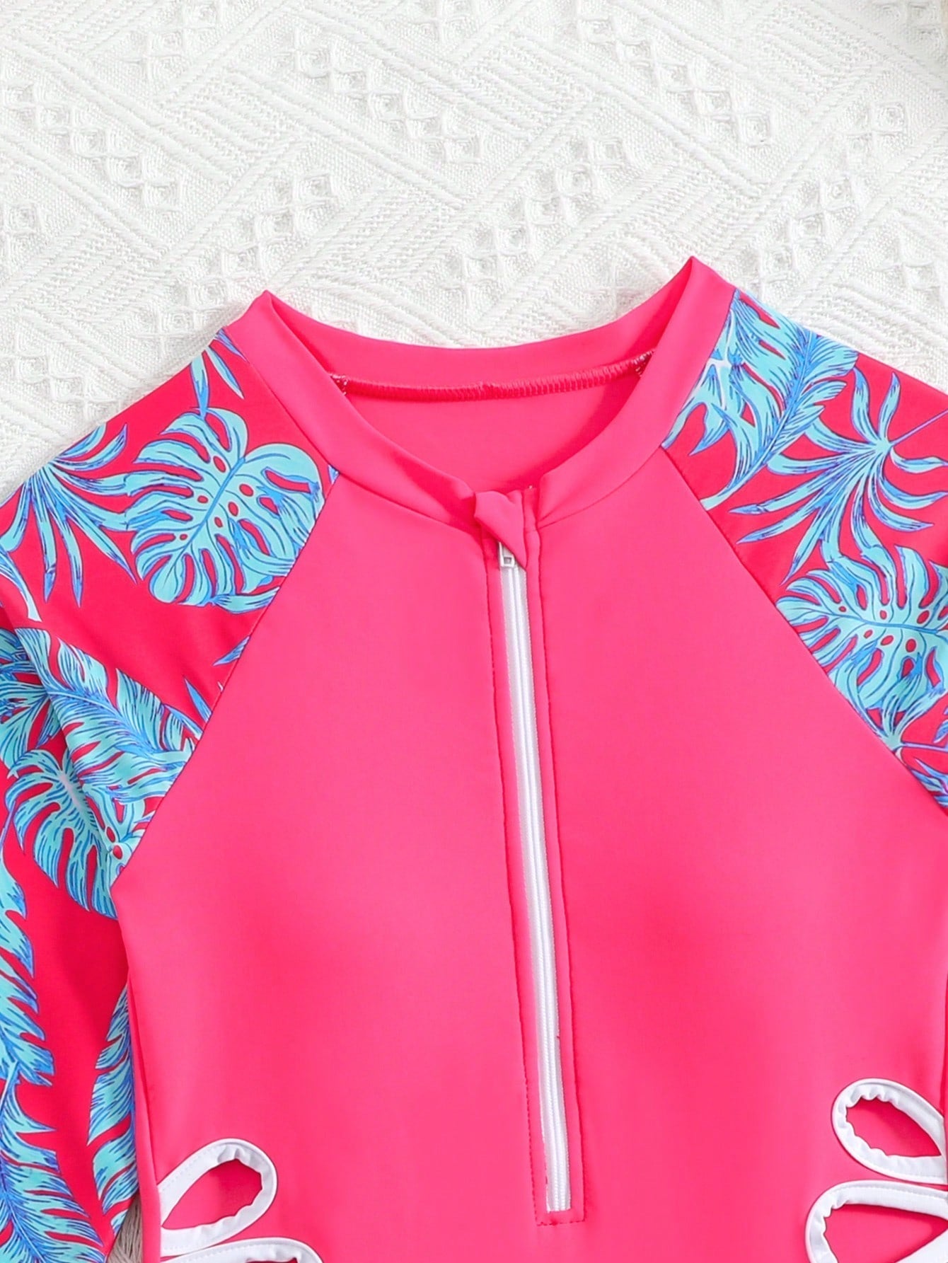 Tween girls one-piece rash guard swimsuit with long sleeves, high neck, front zipper, and ocean shell graphic print in a fitted style for beach, swimming, and vacation wear.